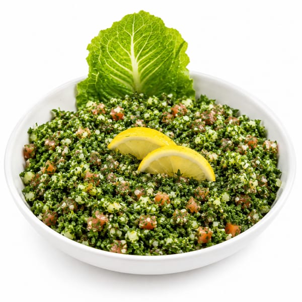 A white bowl filled with vibrant green tabbouleh salad, garnished with lemon slices and lettuce.